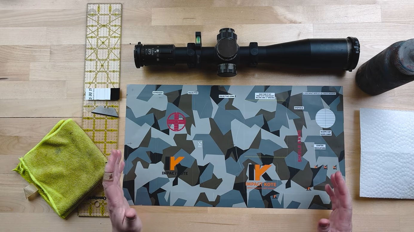 Impact Kote scope wrap installation kit laid out on a table, including a rifle scope, microfiber cloth, ruler, and pre-cut vinyl wrap sheets in a camouflage pattern.